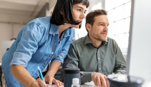 Male and female employees looking at a computer together. 