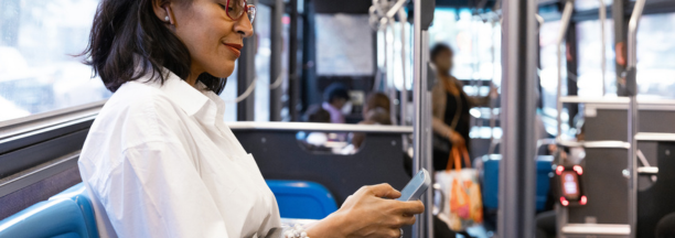 Middle aged woman commuting on a bus while looking down at her phone.